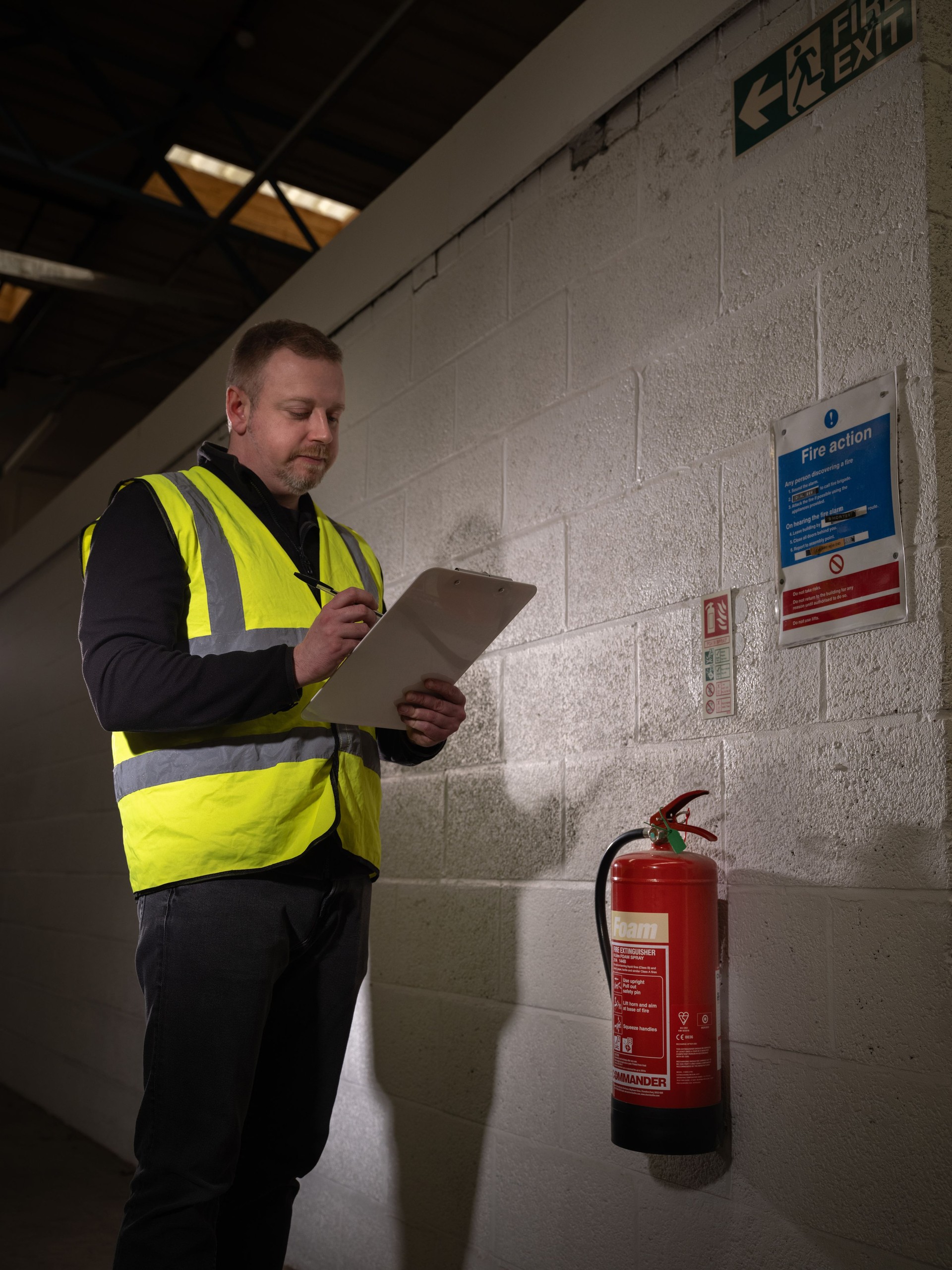 Adult male working as fire safety officer with clipboard, fire extinguisher and safety checklist